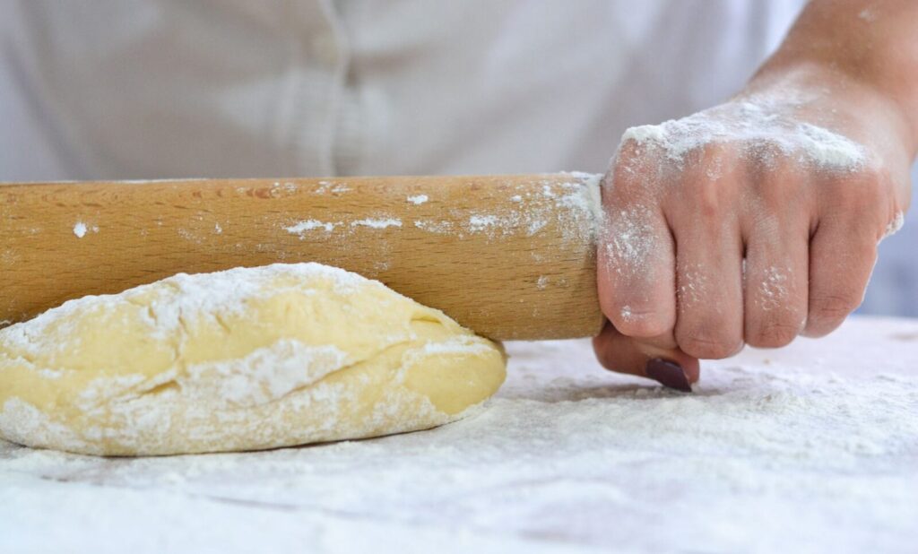 La pâte brisée étalée au rouleau sur un plan de travail fariné