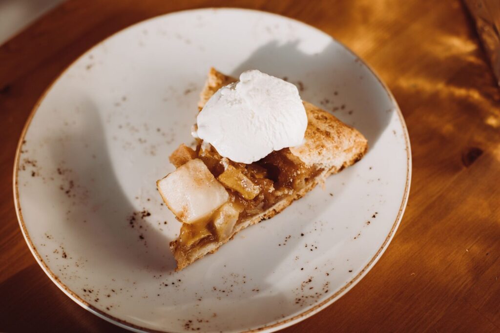 Une part de tarte aux pommes servie sur une assiette blanche